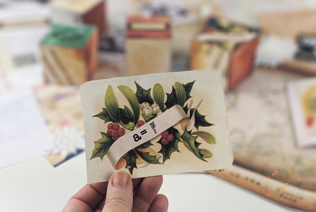 A hand holding a card with Christmas images and clue.
