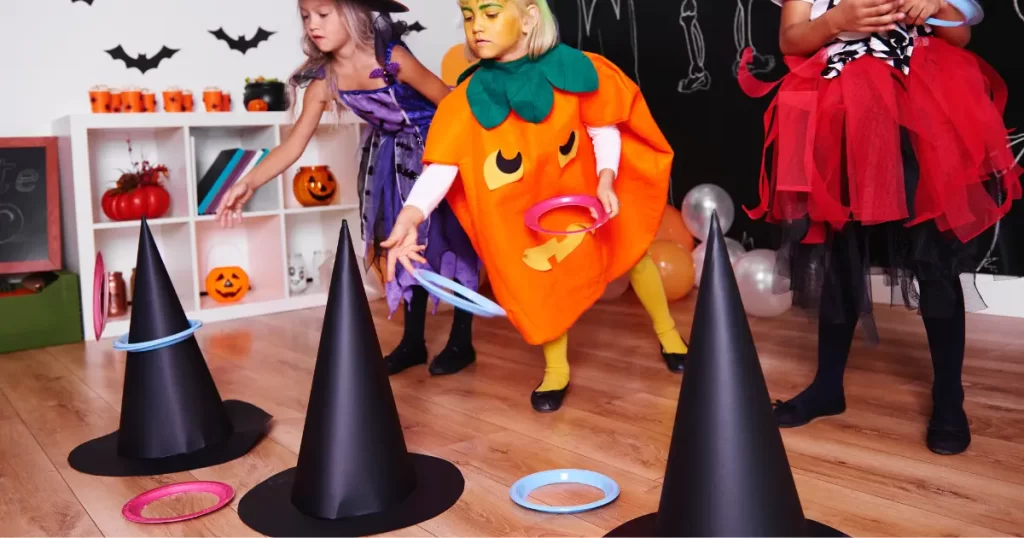 Kids dressed up in Halloween costumes, playing a witch hat ring toss game.