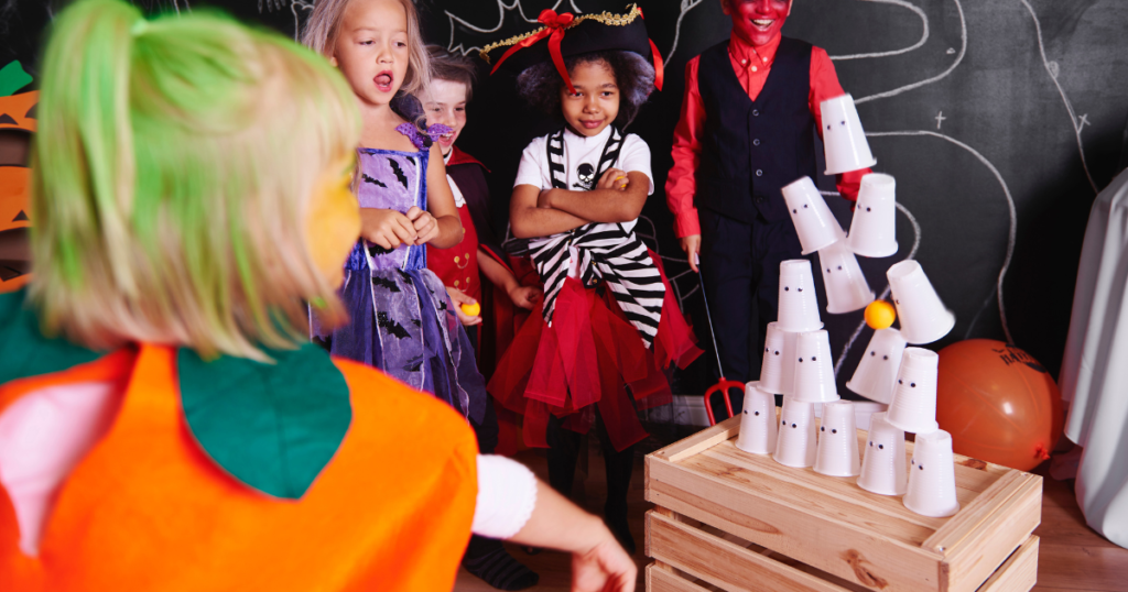 A girl throwing a ball at a pyramid of cups that a made to look like ghosts.