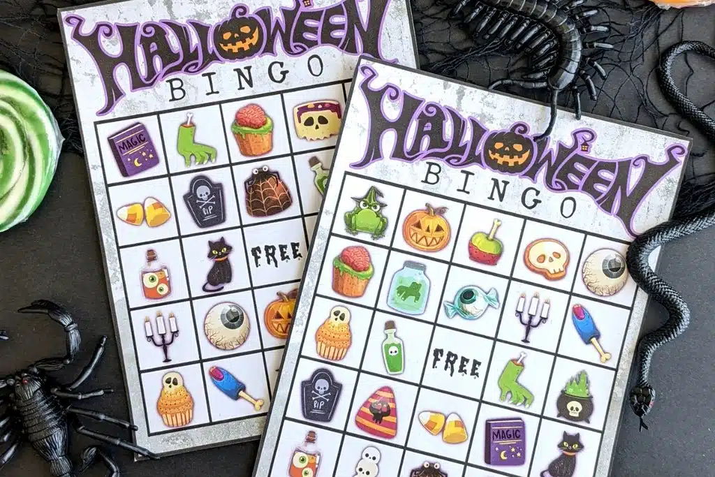 Two Halloween themed bingo boards on a black background surrounded by fake bugs.
