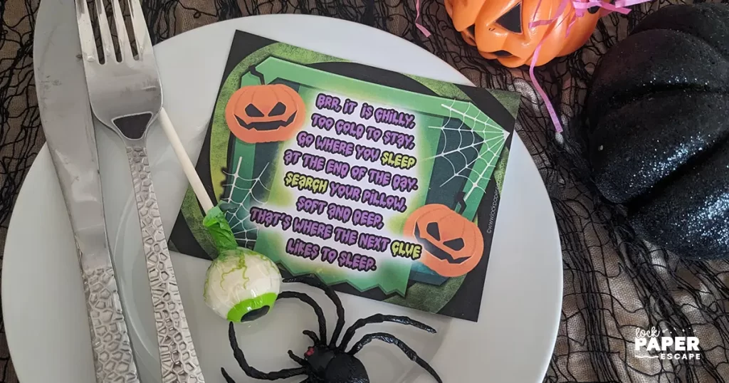 Halloween treasure hut clue placed on aplate with a plastic spider and eyeball lolly.