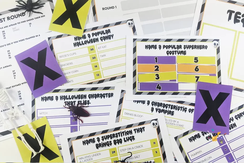 printed Halloween feud game material scattered on a table with fake bugs.