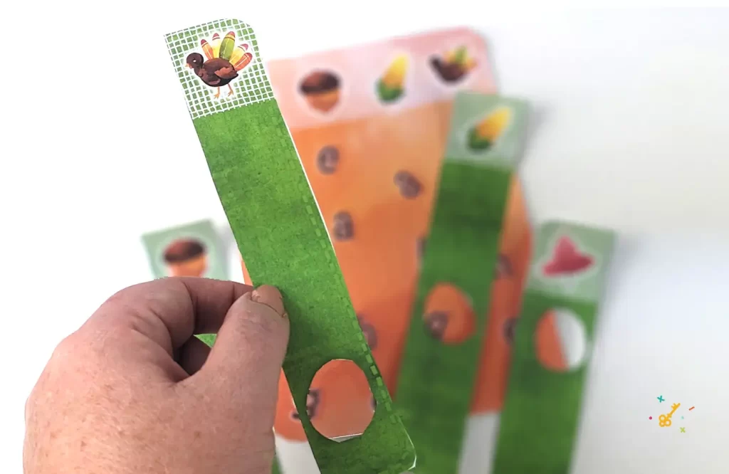 A hand holding a Thanksgiving puzzle piece with a picture of a turkey on it. The remaining puzzle is in the background.