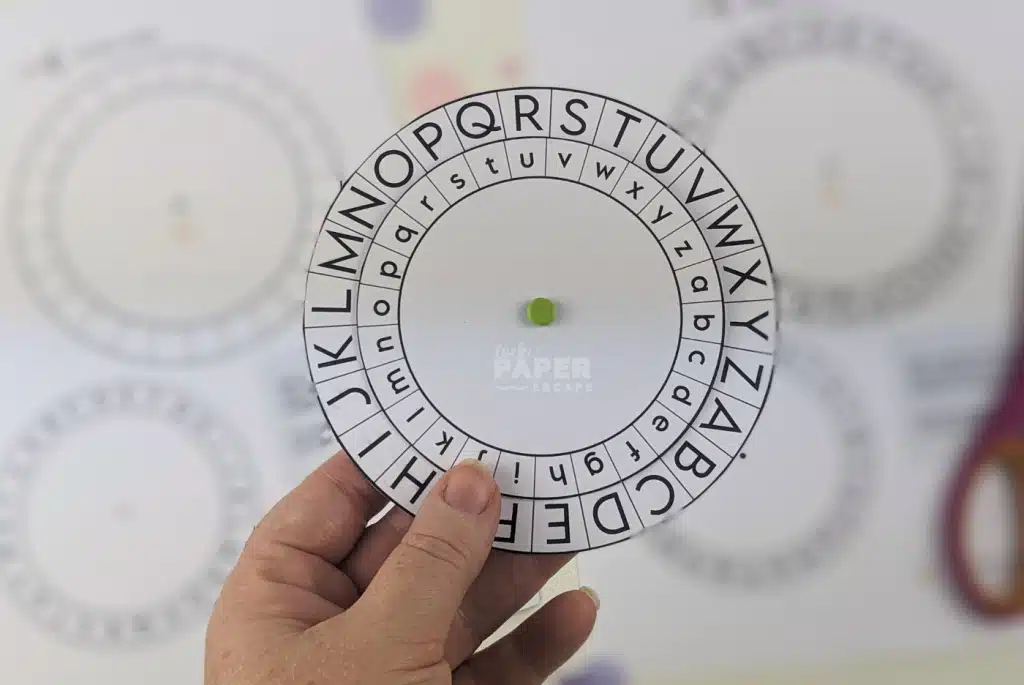 A hand holding a cipher wheel to use in a DIY escape room game.